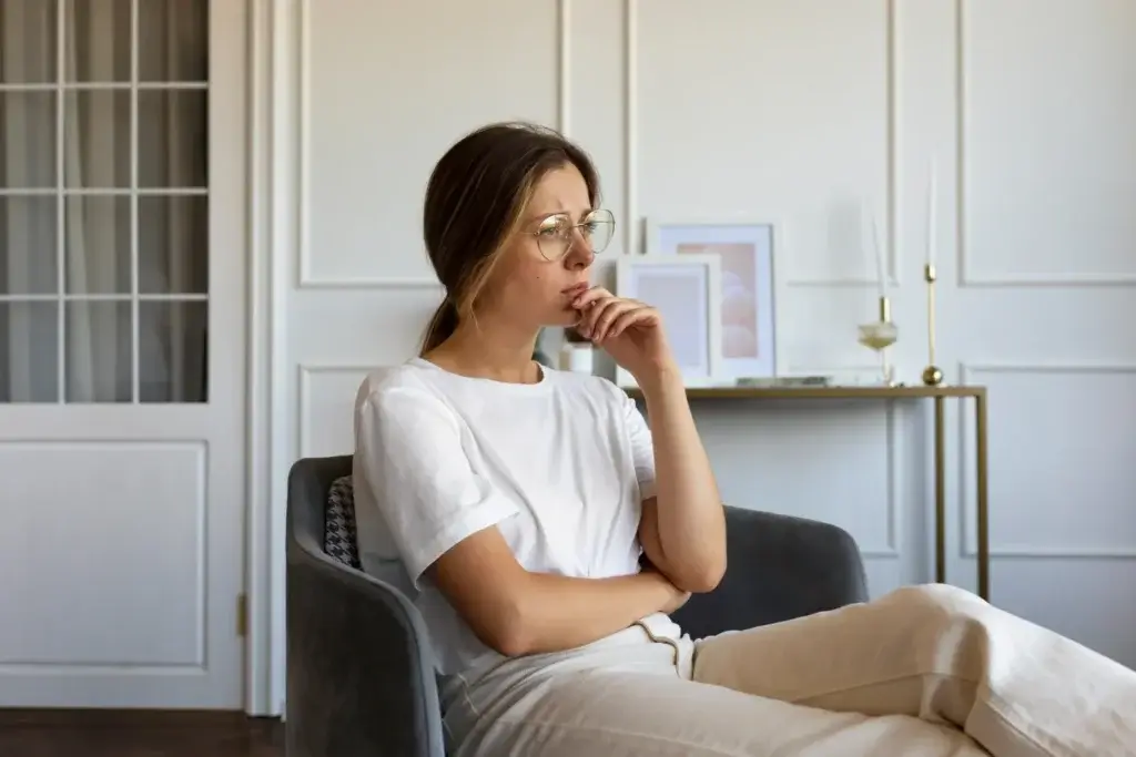 Woman sitting in a chair, reflecting on how often to attend therapy.